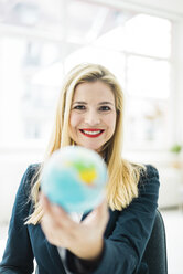 Porträt einer lächelnden Geschäftsfrau mit Mini-Globus - MOEF00219