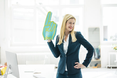 Smiling businesswoman twinkling holding large hand in office - MOEF00223