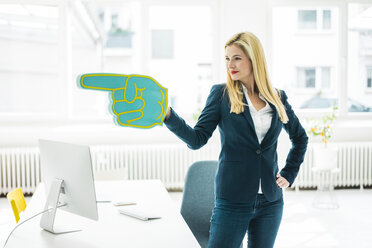 Confident businesswoman pointing with large hand in office - MOEF00225