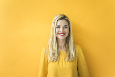 Portrait of smiling woman at yellow wall - MOEF00232