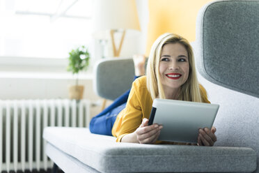 Woman lying on couch using tablet - MOEF00234