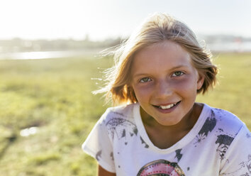 Porträt eines lächelnden blonden Mädchens im Sonnenlicht - MGOF03657