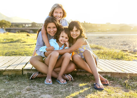 Gruppenfoto von vier Mädchen, die im Sommer auf der Strandpromenade sitzen - MGOF03669