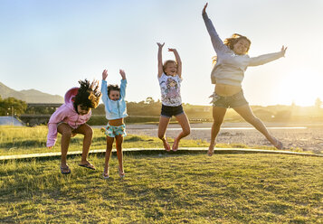 Four happy girls jumping in the air at twilight - MGOF03673