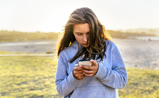 Porträt eines Mädchens, das ein Mobiltelefon im Freien benutzt - MGOF03677