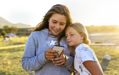 Two girls looking at cell phone outdoors - MGOF03678