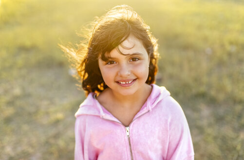 Portrait of smiling little girl with blowing hair at backlight - MGOF03681