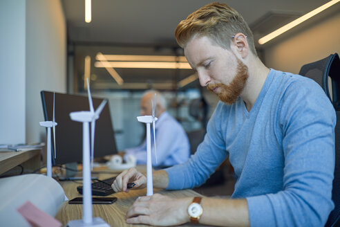 Man in office with model wind turbines - ZEDF00923