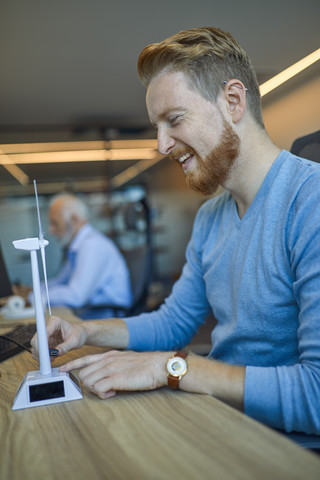 Happy man in office with model wind turbine stock photo