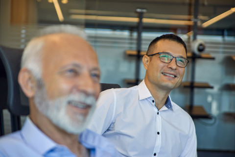 Zwei lächelnde Geschäftsmänner im Büro, lizenzfreies Stockfoto