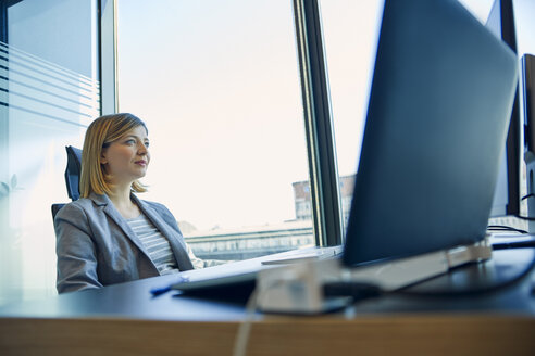 Geschäftsfrau sitzt am Schreibtisch im Büro - ZEDF00938