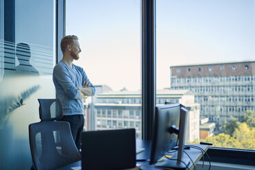 Businessman in office looking out of window - ZEDF00958