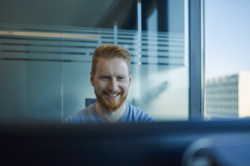 Glücklicher Geschäftsmann am Schreibtisch im Büro - ZEDF00961