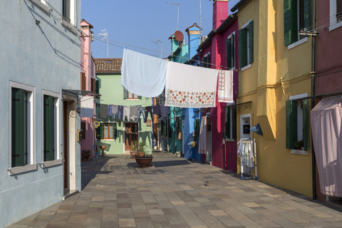 Italien, Lagune von Venedig, Burano, bunte Häuser und zum Trocknen aufgehängte Wäsche, lizenzfreies Stockfoto