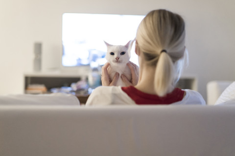 Woman sitting with her cat on the couch watching TV stock photo