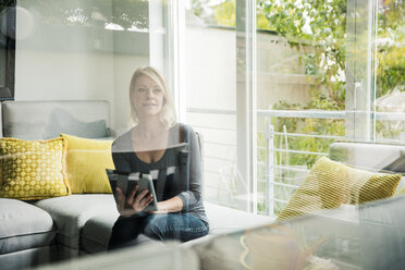 Woman holding tablet on couch - MOEF00241