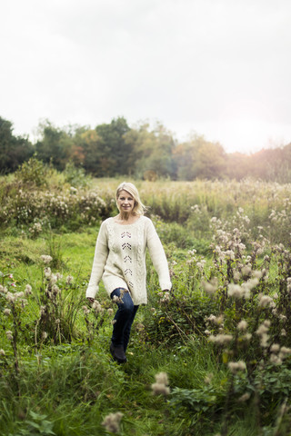 Lächelnde blonde Frau beim Spaziergang in der Natur, lizenzfreies Stockfoto