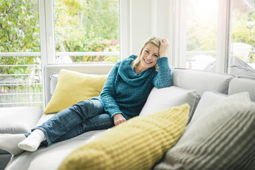 Portrait of happy woman relaxing on couch - MOEF00267