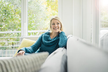 Porträt einer glücklichen Frau, die sich auf der Couch entspannt - MOEF00268