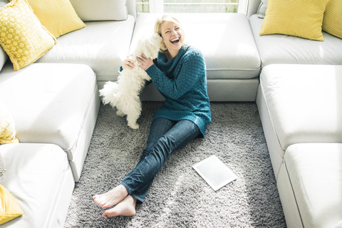 Playful woman with dog in living room stock photo