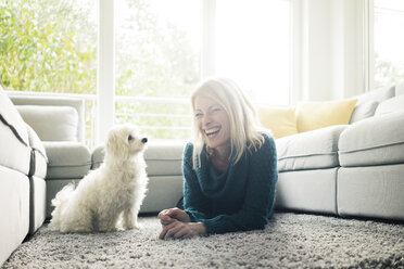 Glückliche Frau mit Hund im Wohnzimmer - MOEF00282