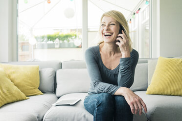 Happy woman on the phone on couch - MOEF00288