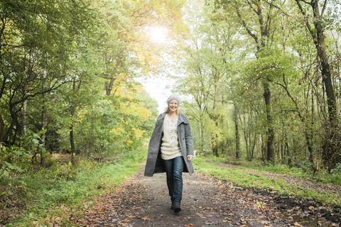 Porträt einer glücklichen Frau, die im Herbst im Wald spazieren geht, lizenzfreies Stockfoto