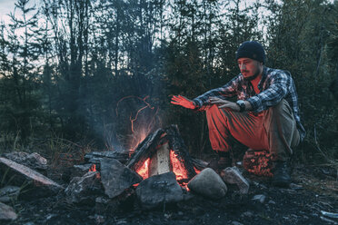 Mann sitzt am Lagerfeuer in ländlicher Landschaft - VPIF00241