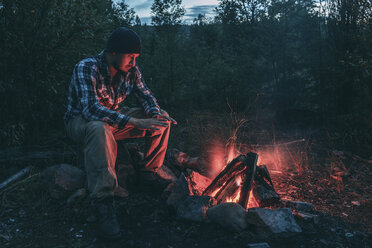 Man sitting at campfire in rural landscape - VPIF00242