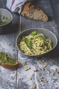 Hausgemachtes Basilikum-Pesto, Spaghetti in einer Schüssel, Roggenbaguette auf Holz - ODF01561