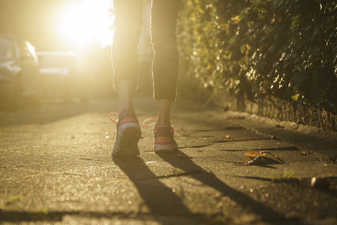 Legs of woman jogging on walkway at sunset stock photo