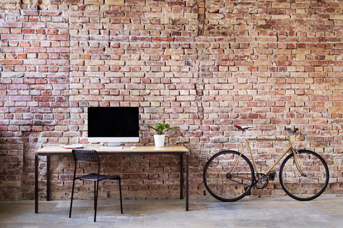 Workspace and bicycle at brick wall in office - HAPF02339