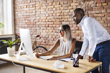 Two colleagues working together at desk in office - HAPF02401