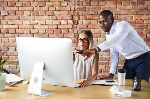 Zwei Kollegen arbeiten zusammen am Schreibtisch im Büro - HAPF02402