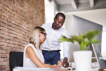 Two colleagues working together at desk in office - HAPF02403