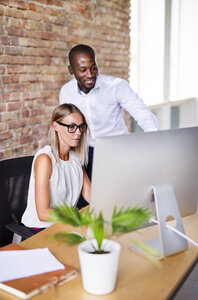 Zwei Kollegen arbeiten zusammen am Schreibtisch im Büro - HAPF02404