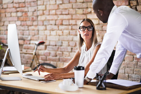 Zwei Kollegen arbeiten zusammen am Schreibtisch im Büro - HAPF02409