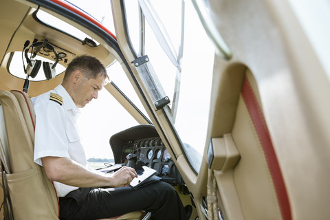 Pilot benutzt Tablet im Cockpit eines Hubschraubers, lizenzfreies Stockfoto