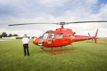 Porträt eines Piloten, der neben einem roten Hubschrauber steht - OJF00200