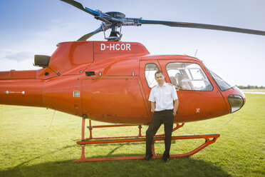 Porträt eines Piloten, der neben einem roten Hubschrauber steht - OJF00203