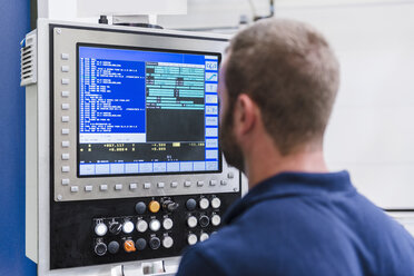 Mann schaut auf einen Bildschirm in einer industriellen Fabrik - DIGF03100