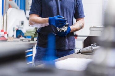 Close-up of man holding tool in industrial factory - DIGF03102