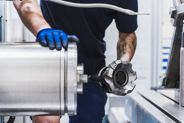 Close-up of man holding workpiece in industrial factory - DIGF03115