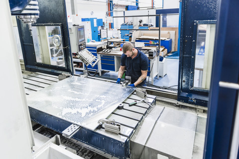 Mann arbeitet an einer Maschine in einer industriellen Fabrik, lizenzfreies Stockfoto