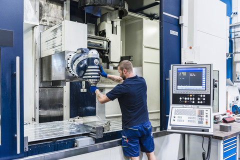 Mann arbeitet an einer Maschine in einer industriellen Fabrik, lizenzfreies Stockfoto