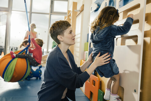 Vorschullehrerin hilft kleinem Mädchen beim Klettern an einer Wand - MFF04049