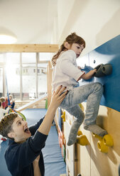 Pre-school teacher helping little girl climbing up a wall - MFF04053