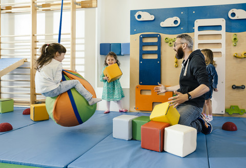 Pre-school teacher and happy children playing in gym room in kindergarten stock photo