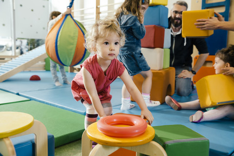 Kleines Mädchen spielt im Turnraum eines Kindergartens, lizenzfreies Stockfoto