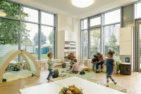 Vorschullehrerin und Kinder beim Spielen im Lernraum des Kindergartens, lizenzfreies Stockfoto